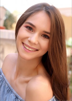 Красивая девушка поджимает губы после того, как обнажила свои маленькие сиськи в саду